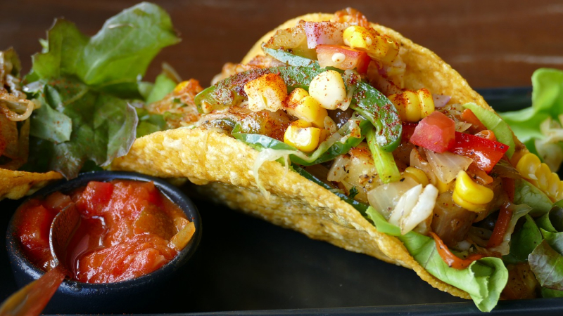 Prim-plan cu un taco, mâncare mexicană tradițională, și un mic bol de sos salsa